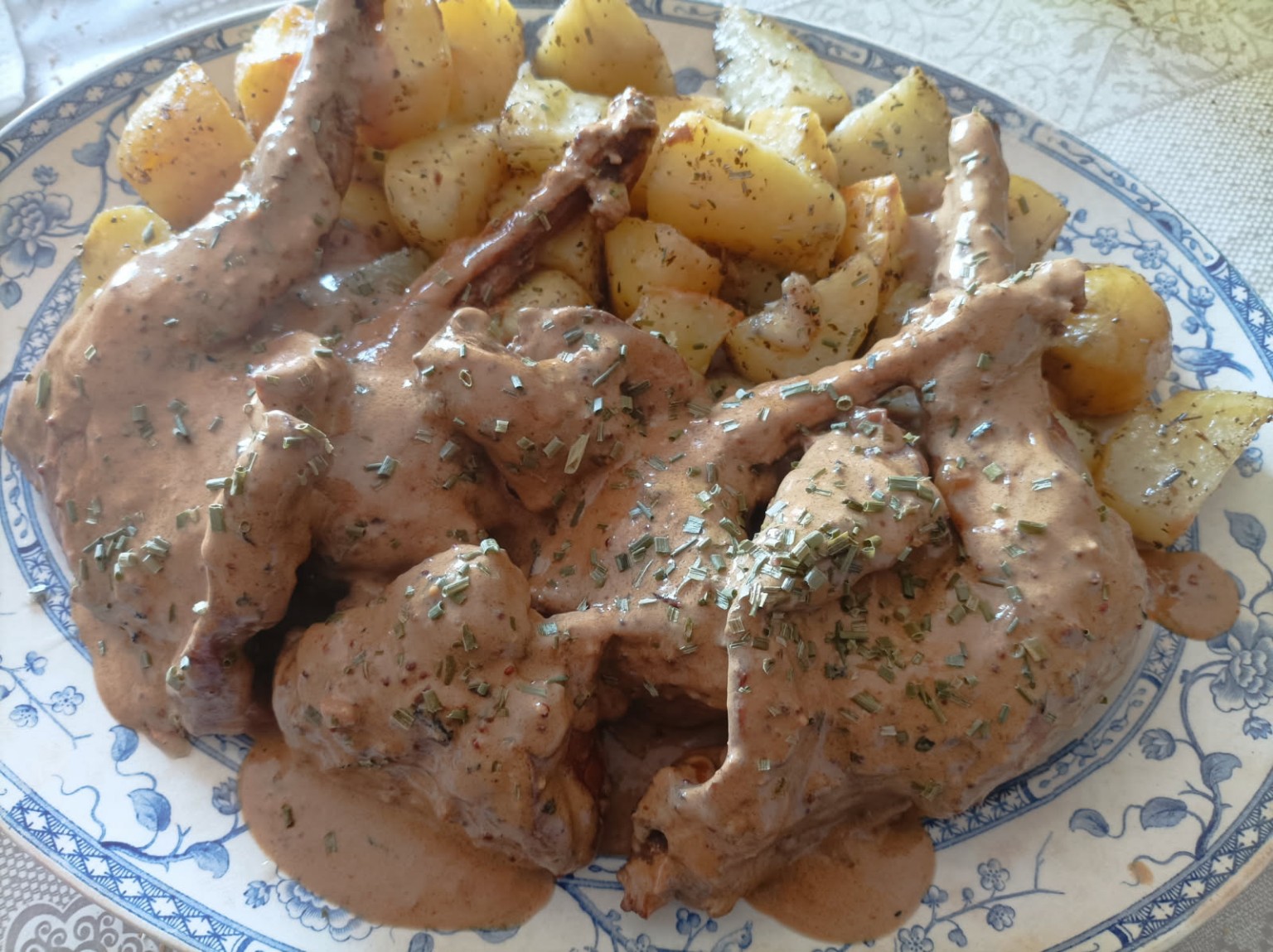 Lapin à la moutarde à l’ancienne avec pommes de terre rôties sur plat en faïence rustique