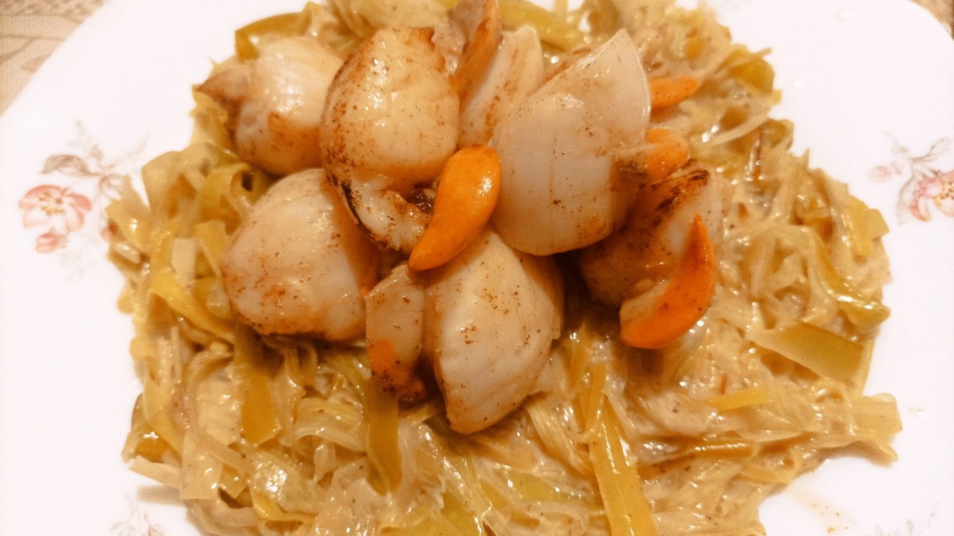 Poêlée de noix de Saint-Jacques servies sur une fondue de poireaux crémeuse.