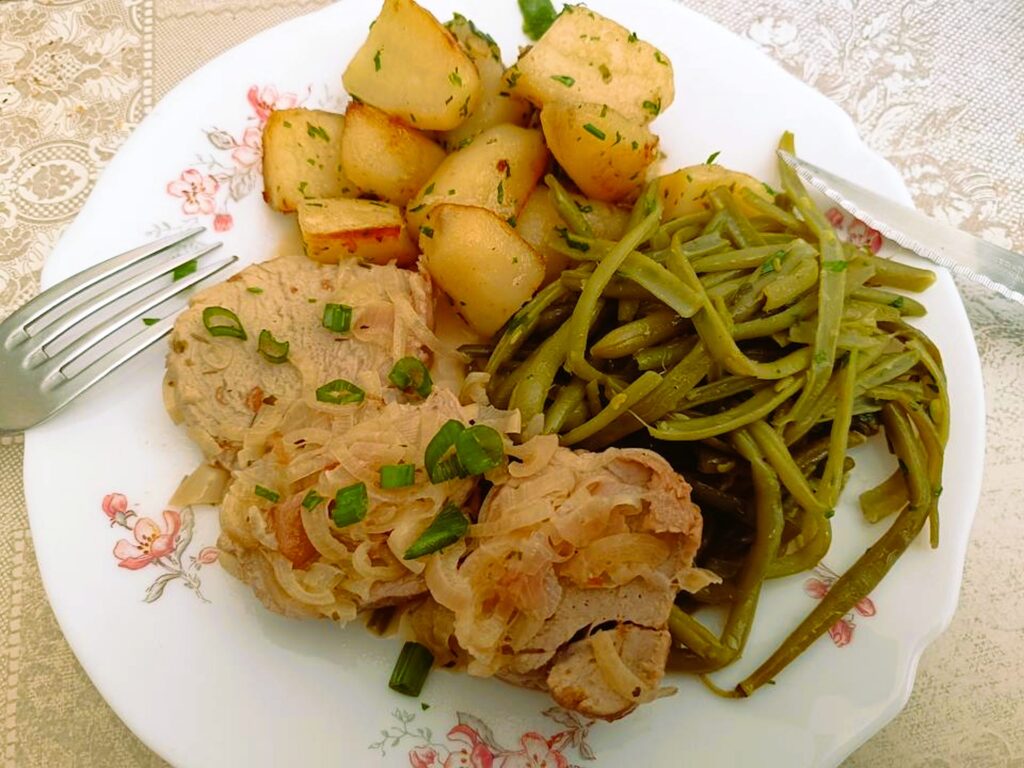 Filet mignon de porc à la normande nappé d'oignons fondants, accompagné de pommes de terre sautées et de haricots verts.